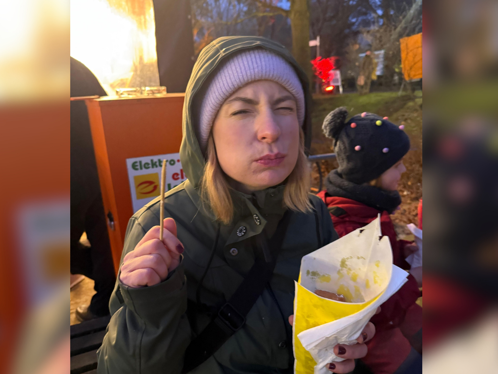 Eine Frau isst aus einer Tüte Pommes und kneift dabei die Augen zu. Eine Frau isst aus einer Tüte Pommes und kneift dabei die Augen zu.