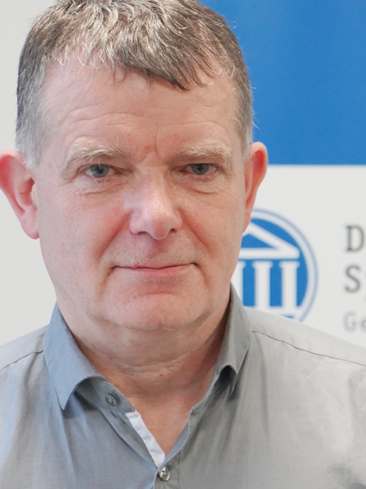 Ein Mann in einem grauen Hemd, im Hintergrund das Spoho Logo Köln