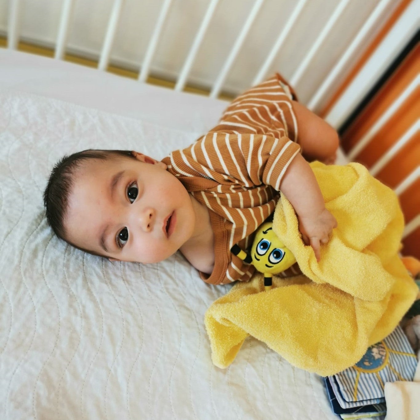 Baby Ben-Louis liegt auf einem Bett mit einer gelben Decke Baby Ben-Louis liegt auf einem Bett mit einer gelben Decke