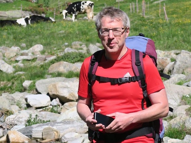 Ein Mann steht vor einem Fluss mit einer Kuh im Hintergrund Ein Mann steht vor einem Fluss mit einer Kuh im Hintergrund