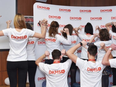 Eine Gruppe von Menschen trägt DKMS T-Shirts und steht mit dem Rücken zur Kamera Eine Gruppe von Menschen trägt DKMS T-Shirts und steht mit dem Rücken zur Kamera
