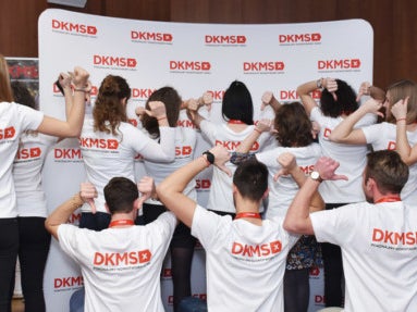 Eine Gruppe von Menschen trägt DKMS T-Shirts und steht mit dem Rücken zur Kamera Eine Gruppe von Menschen trägt DKMS T-Shirts und steht mit dem Rücken zur Kamera