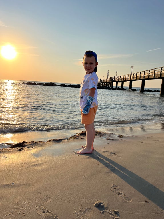 Patient Miko steht am Strand mit dem Sonnenuntergang im Hintergrund. Patient Miko steht am Strand mit dem Sonnenuntergang im Hintergrund.