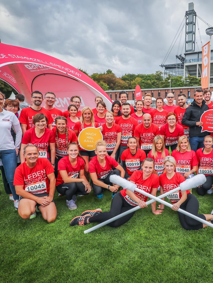 Gruppenfoto von DKMS-Mitarbeitenden in roten „Leben Spenden Läuft“-Shirts vor einem Zelt auf einer Wiese. Gruppenfoto von DKMS-Mitarbeitenden in roten „Leben Spenden Läuft“-Shirts vor einem Zelt auf einer Wiese.
