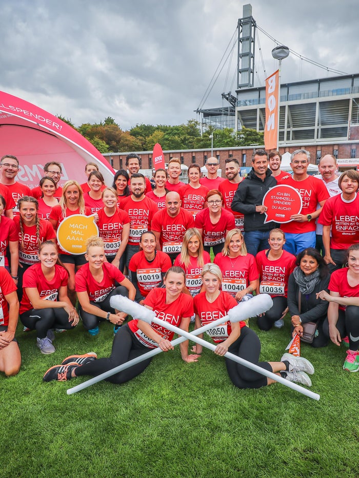 Gruppenfoto von DKMS-Mitarbeitenden in roten „Leben Spenden Läuft“-Shirts vor einem Zelt auf einer Wiese. Gruppenfoto von DKMS-Mitarbeitenden in roten „Leben Spenden Läuft“-Shirts vor einem Zelt auf einer Wiese.