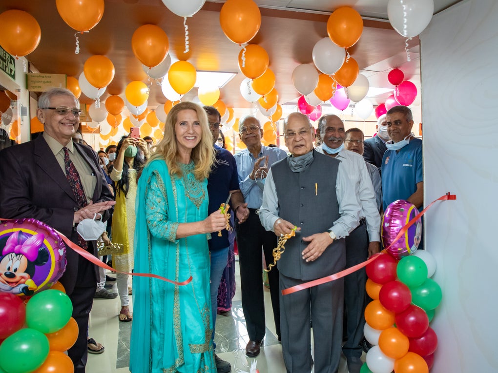 Eine Gruppe von Menschen, die in einem Raum mit Luftballons stehen, sie zerschneiden ein Band Eine Gruppe von Menschen, die in einem Raum mit Luftballons stehen, sie zerschneiden ein Band