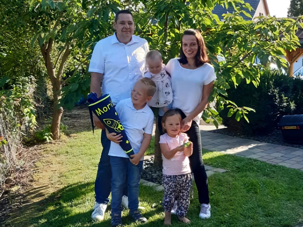 Eine Familie steht im Garten, eines der Kinder hält eine Einschulungstüte. Eine Familie steht im Garten, eines der Kinder hält eine Einschulungstüte.
