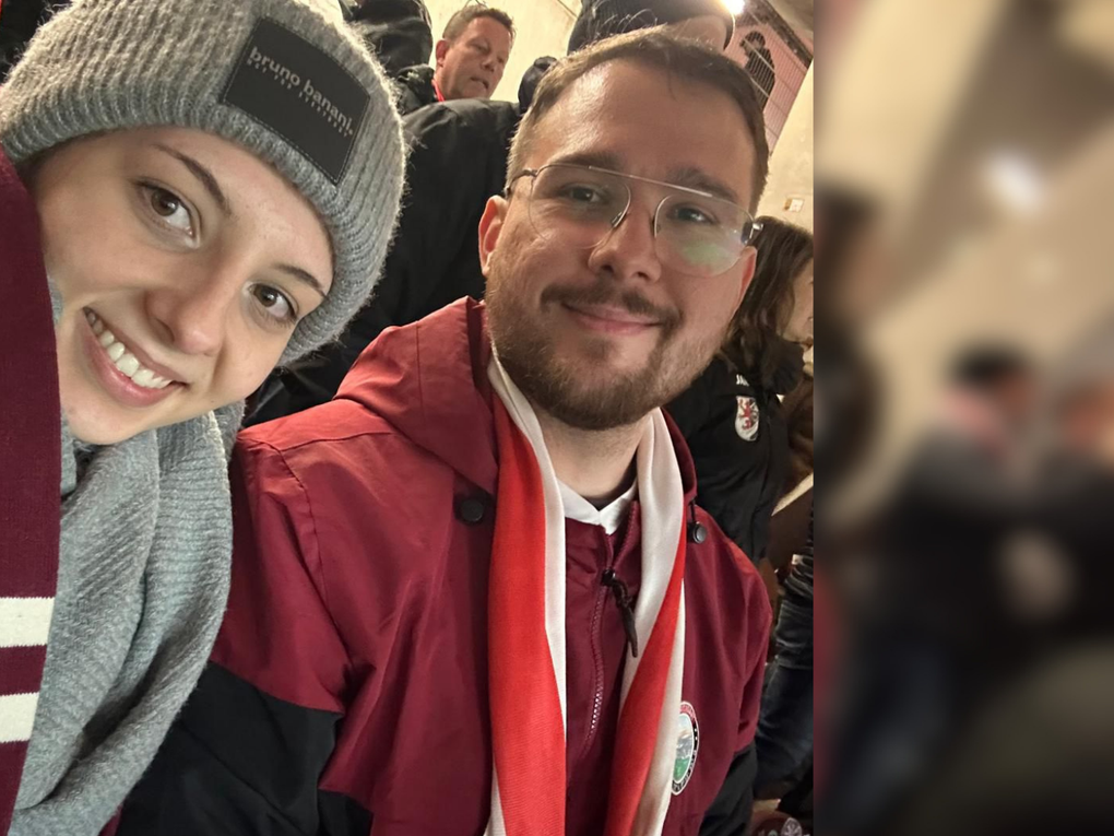 Eine Frau und ein Mann tragen Fanartikel eines Sportvereins und nehmen ein Selfie auf. Eine Frau und ein Mann tragen Fanartikel eines Sportvereins und nehmen ein Selfie auf.
