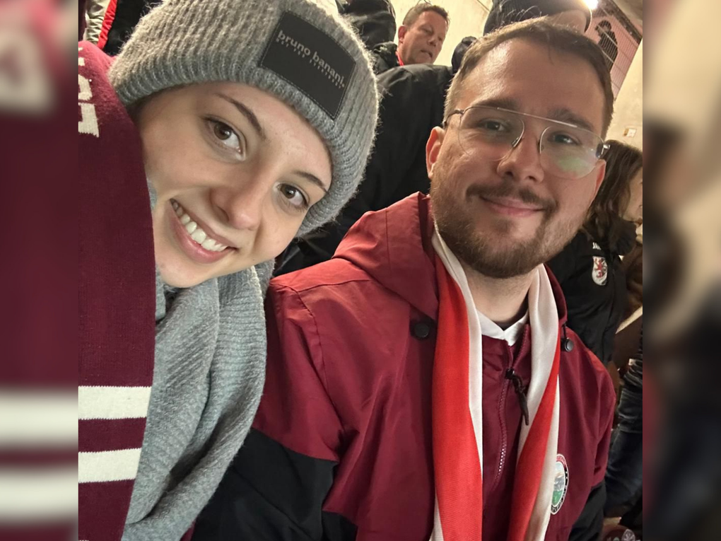 Eine Frau und ein Mann tragen Fanartikel eines Sportvereins und nehmen ein Selfie auf. Eine Frau und ein Mann tragen Fanartikel eines Sportvereins und nehmen ein Selfie auf.