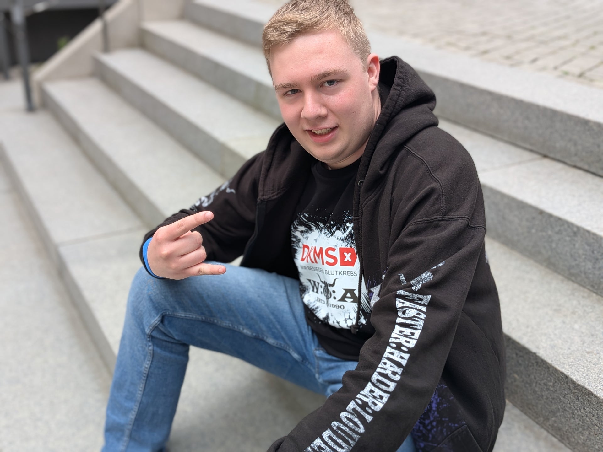 Ein Mann sitzt auf einer Treppe mit DKMS-Oberteil Ein Mann sitzt auf einer Treppe mit DKMS-Oberteil