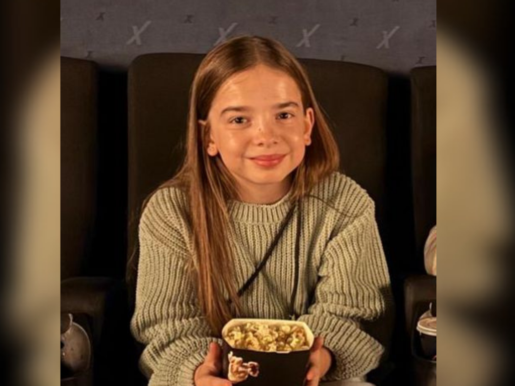 Ein Mädchen sitzt in einem Kinosessel und hält eine Tüte Popcorn in den Händen. Ein Mädchen sitzt in einem Kinosessel und hält eine Tüte Popcorn in den Händen.