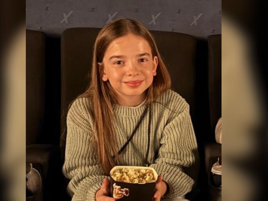 Ein Mädchen sitzt in einem Kinosessel und hält eine Tüte Popcorn in den Händen. Ein Mädchen sitzt in einem Kinosessel und hält eine Tüte Popcorn in den Händen.