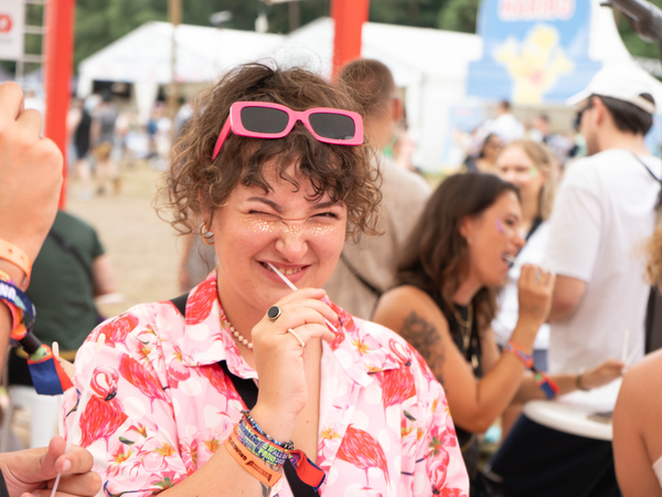 Eine junge Frau steht auf einem Festivalgelände und macht einen Wangenabstrich Eine junge Frau steht auf einem Festivalgelände und macht einen Wangenabstrich