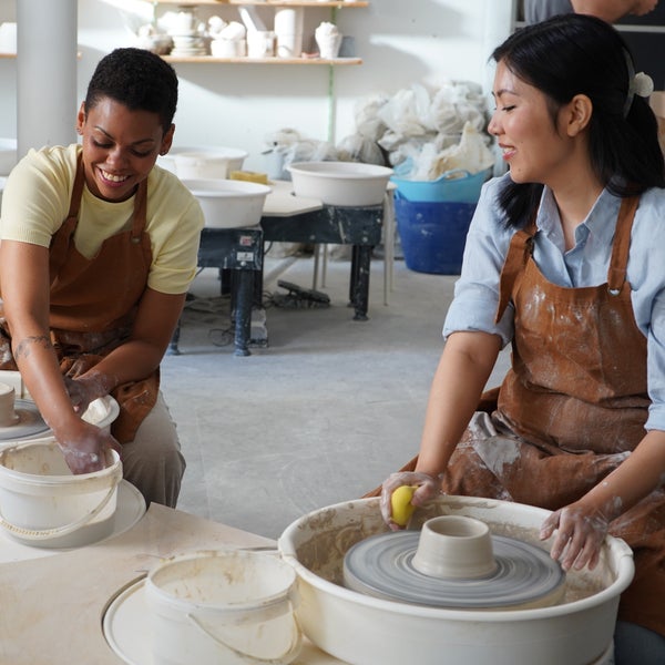 Zwei Frauen sitzen an Töpferscheiben und arbeiten mit Ton. Zwei Frauen sitzen an Töpferscheiben und arbeiten mit Ton.