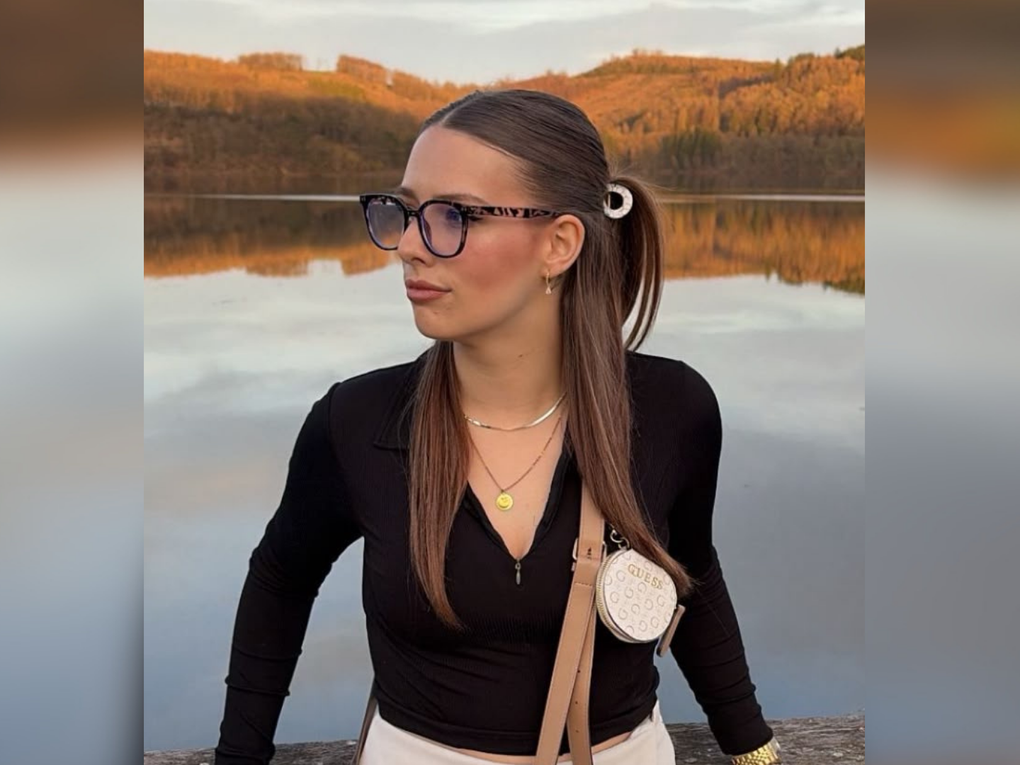Eine Frau trägt Brille und steht vor einem See. Eine Frau trägt Brille und steht vor einem See.