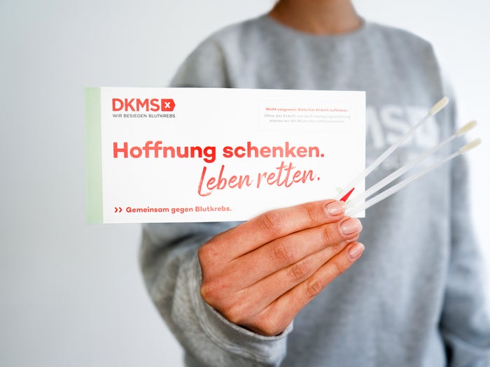 Eine Person hält ein DKMS-Registrierungsset mit der Aufschrift "Hoffnung schenken. Leben retten." und drei Wattestäbchen. Eine Person hält ein DKMS-Registrierungsset mit der Aufschrift "Hoffnung schenken. Leben retten." und drei Wattestäbchen.