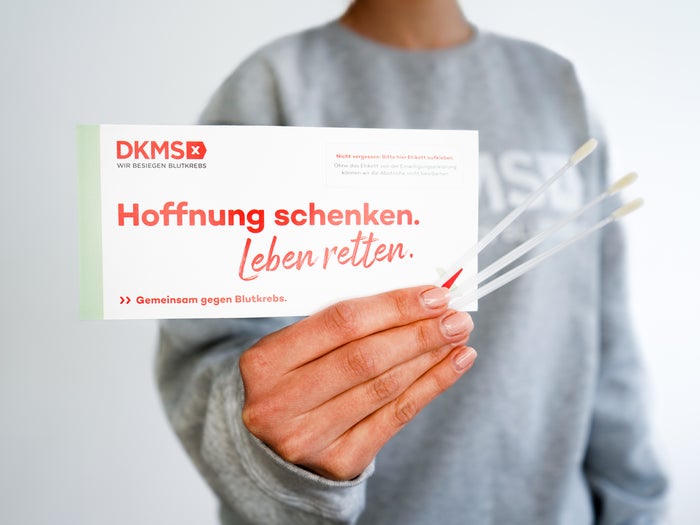 Eine Person hält ein DKMS-Registrierungsset mit der Aufschrift "Hoffnung schenken. Leben retten." und drei Wattestäbchen. Eine Person hält ein DKMS-Registrierungsset mit der Aufschrift "Hoffnung schenken. Leben retten." und drei Wattestäbchen.