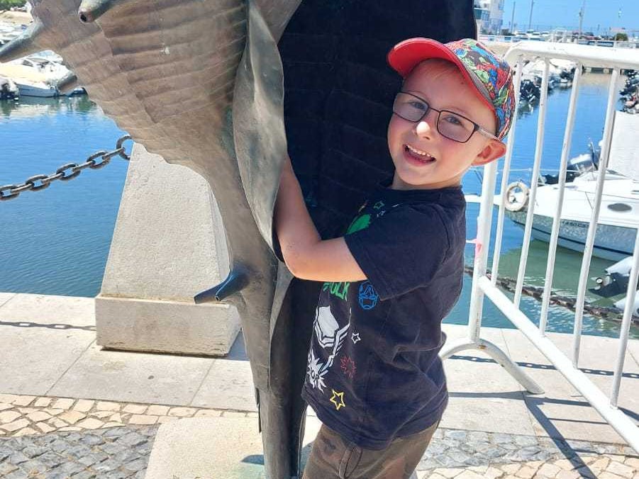 ein Junge posiert mit einer Muschel-Statue ein Junge posiert mit einer Muschel-Statue