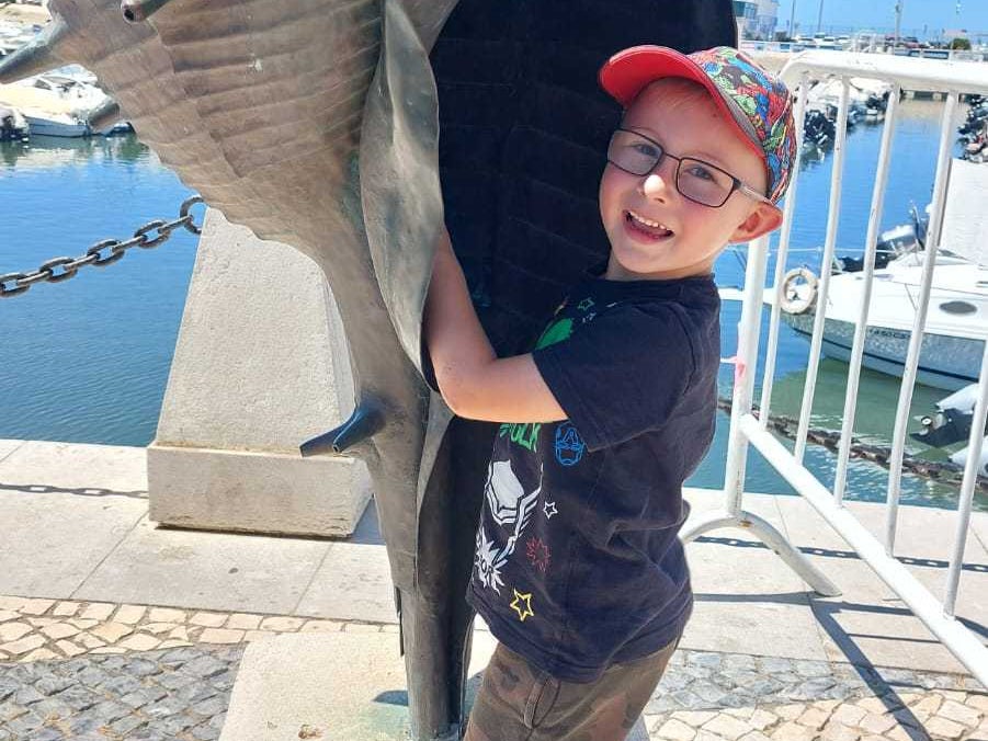 ein Junge posiert mit einer Muschel-Statue ein Junge posiert mit einer Muschel-Statue