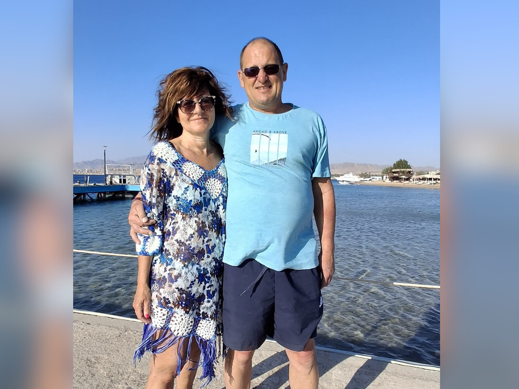 Eine Frau und ein Mann stehen Arm in Arm und sommerlich bekleidet an einem Pier. Eine Frau und ein Mann stehen Arm in Arm und sommerlich bekleidet an einem Pier.