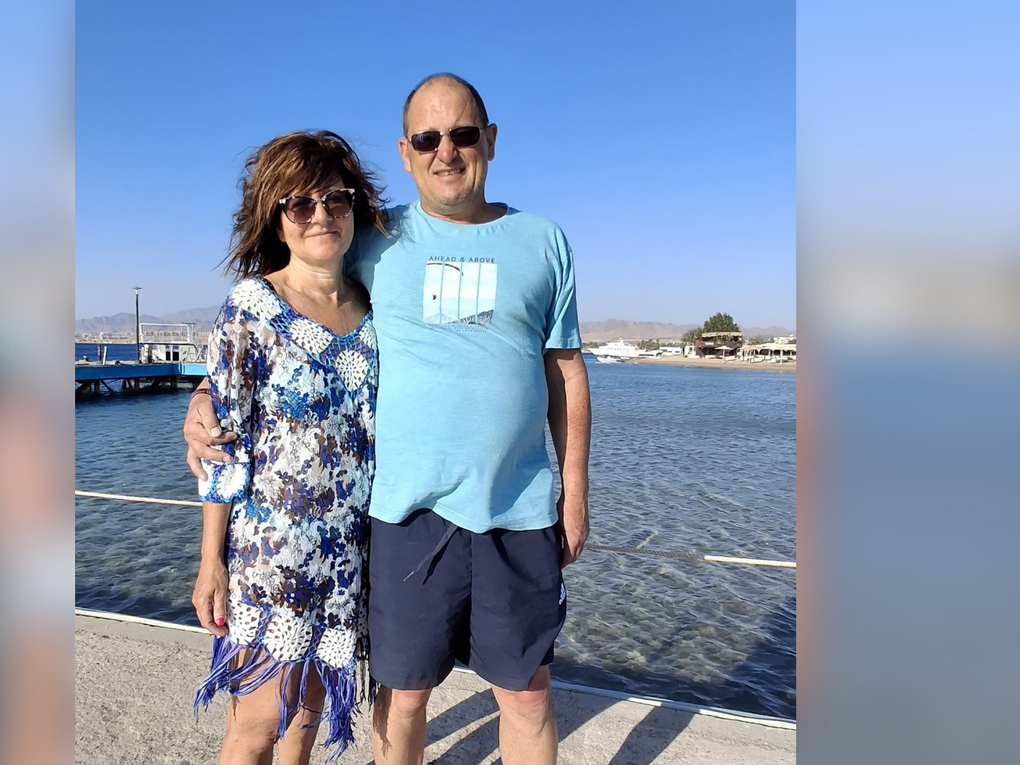 Eine Frau und ein Mann stehen Arm in Arm und sommerlich bekleidet an einem Pier. Eine Frau und ein Mann stehen Arm in Arm und sommerlich bekleidet an einem Pier.