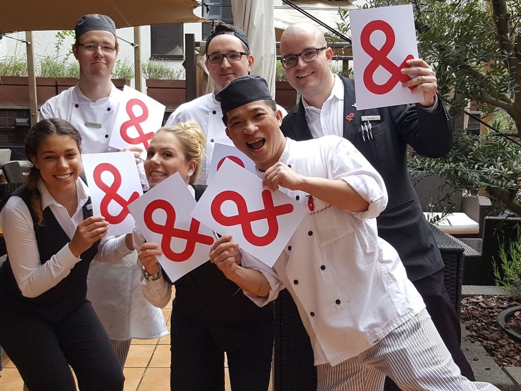 Eine Gruppe von Menschen hält weiße Zettel mit dem Logo der DKMS Eine Gruppe von Menschen hält weiße Zettel mit dem Logo der DKMS