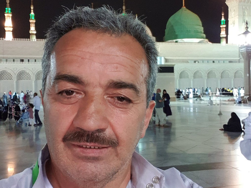 Ein Mann macht ein Selfie auf einem hell erleuchteten Platz vor der Prophetenmoschee in Medina. Im Hintergrund sind die grüne Kuppel und mehrere beleuchtete Minarette zu sehen. Der Mann trägt ein helles Hemd mit einem grünen Umhängeband und blickt direkt in die Kamera. Ein Mann macht ein Selfie auf einem hell erleuchteten Platz vor der Prophetenmoschee in Medina. Im Hintergrund sind die grüne Kuppel und mehrere beleuchtete Minarette zu sehen. Der Mann trägt ein helles Hemd mit einem grünen Umhängeband und blickt direkt in die Kamera.