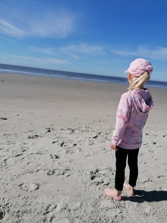 Mila steht am Strand und blickt aufs Wasser. Mila steht am Strand und blickt aufs Wasser.