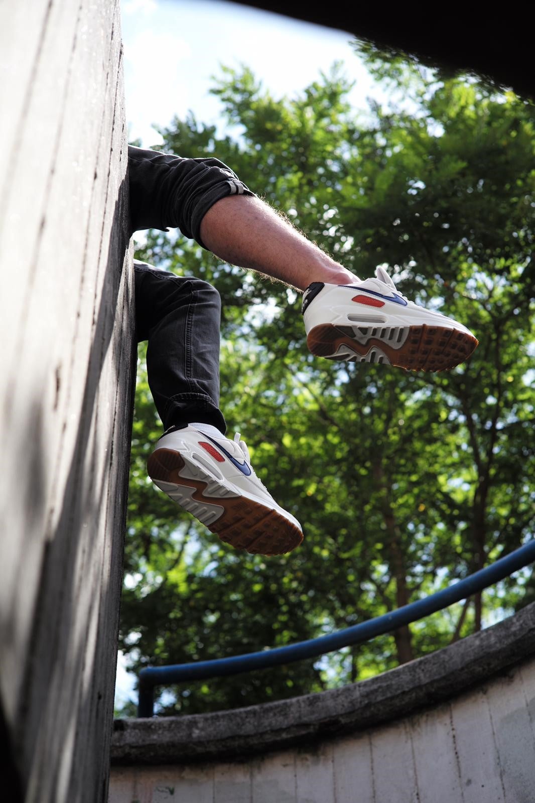 Image shows the underside of the trainers. Taken from underneath, it shows someone's legs dangling over a wall. 