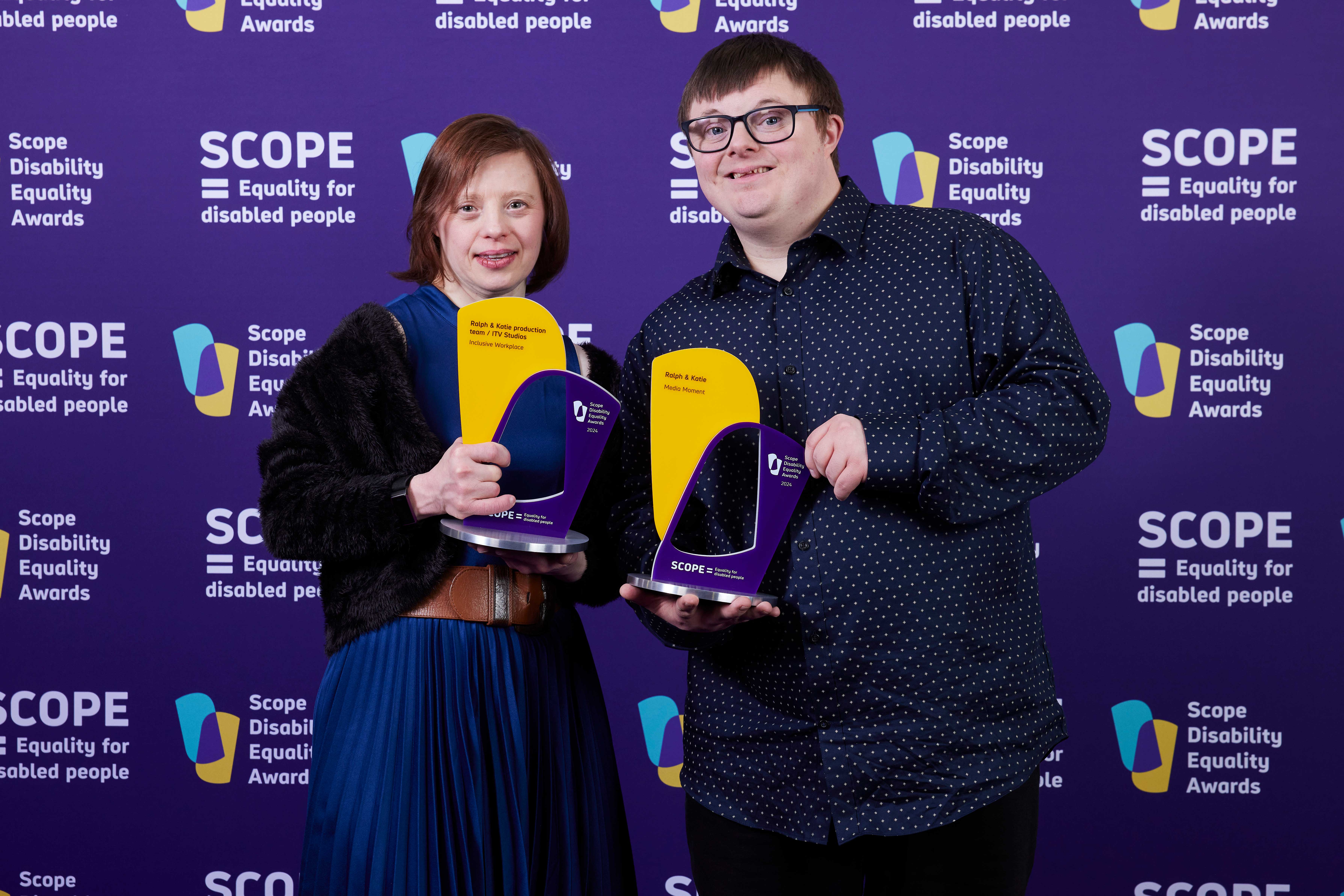 A man and woman holding awards