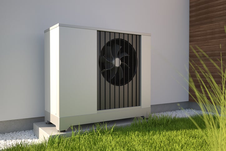 A commercial heat pump situated outside the wall of a business premises