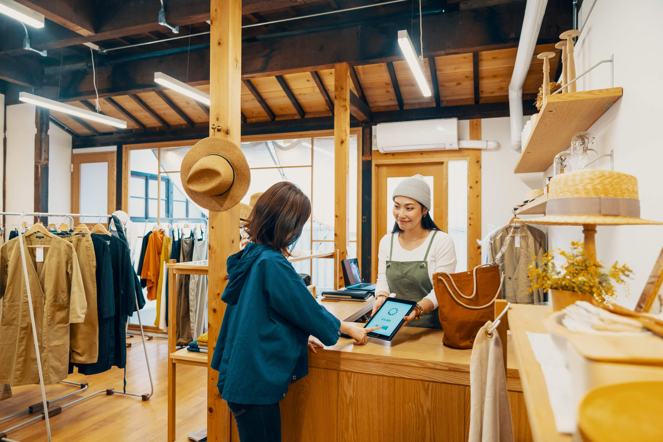 A shoper buys an item in a local clothes store on Small Business Saturday while the shop owner look on.