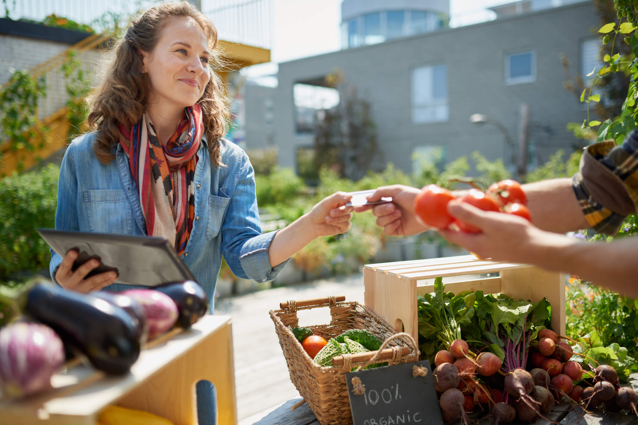 A green grocer sells organic crops and picking up a bountiful basket full of fresh produce in a community pop up store