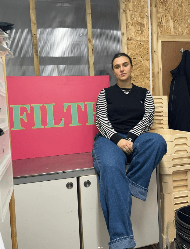 Rosy Sida, owner of Filth Florist, sat next to a sign showing the company logo