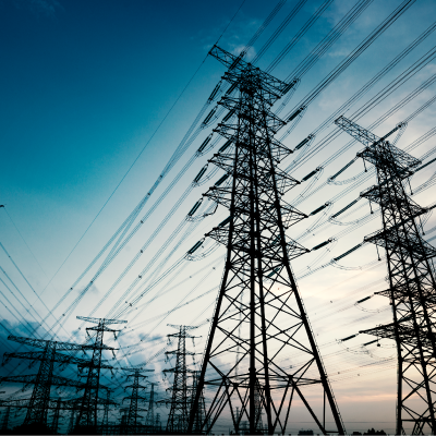 Pylons providing electricity to large business silhouetted against morning sky