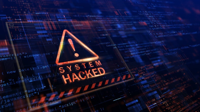 A computer screen shows a 'system hacked' error message on it in orange lettering 