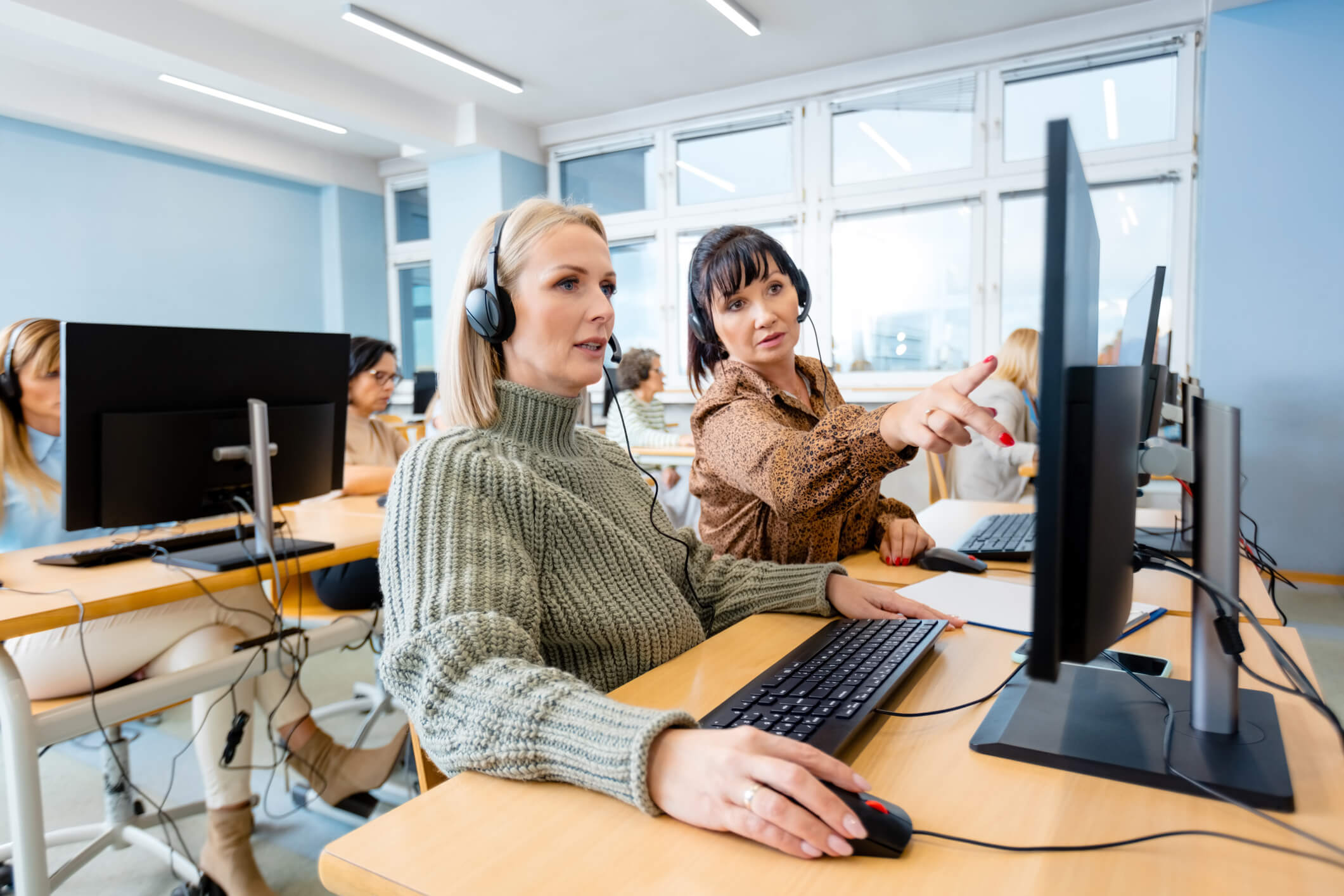 An employee undertakes training on a laptop. Her manager is teaching her new skills.