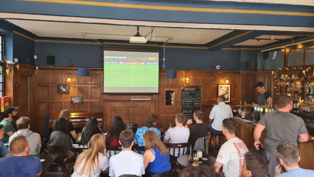 A crowd of pub-goers watch a football match in The Old Justice Pub