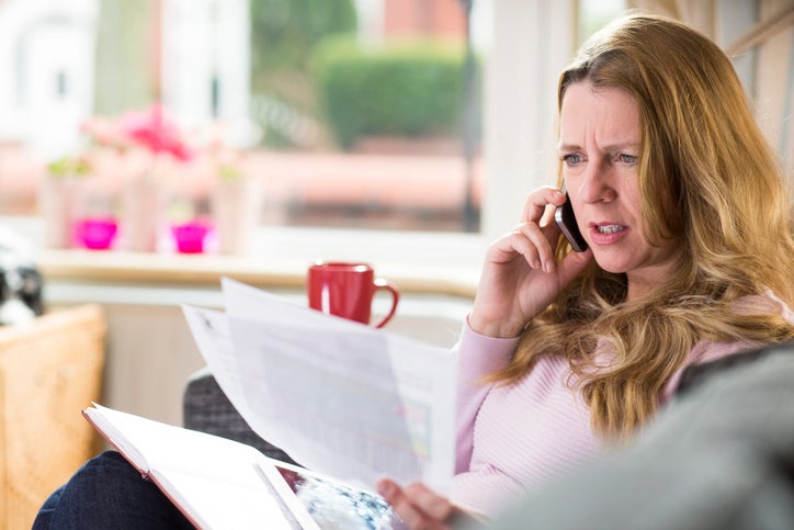 A woman rings holding an energy bill phones to make a complaint about her energy company