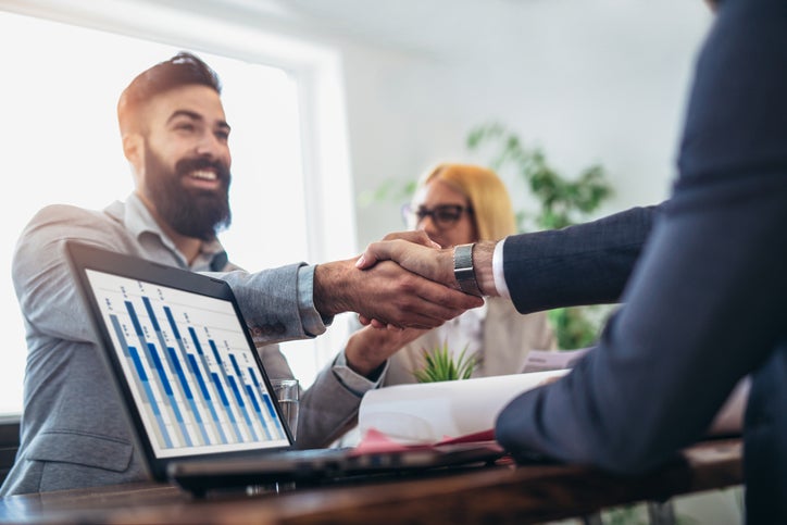 Young business people shaking hands in an office after selling their business