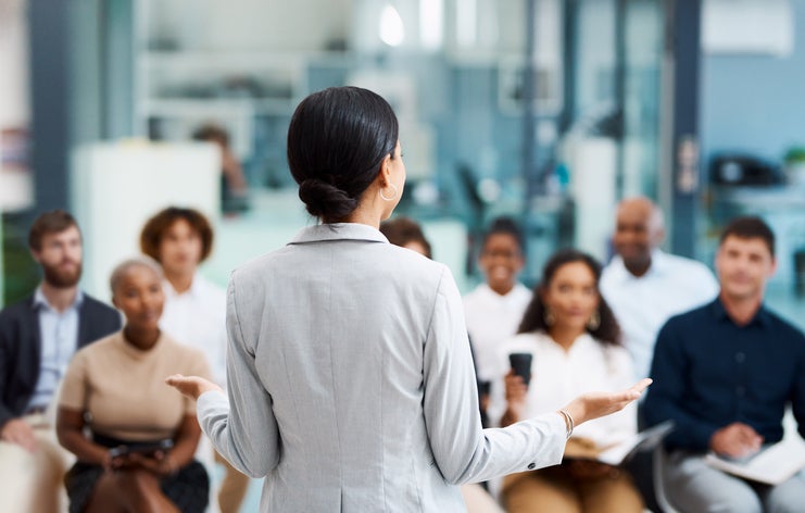 Rearview shot of a businesswoman explaining to employees their rights as she is selling the business