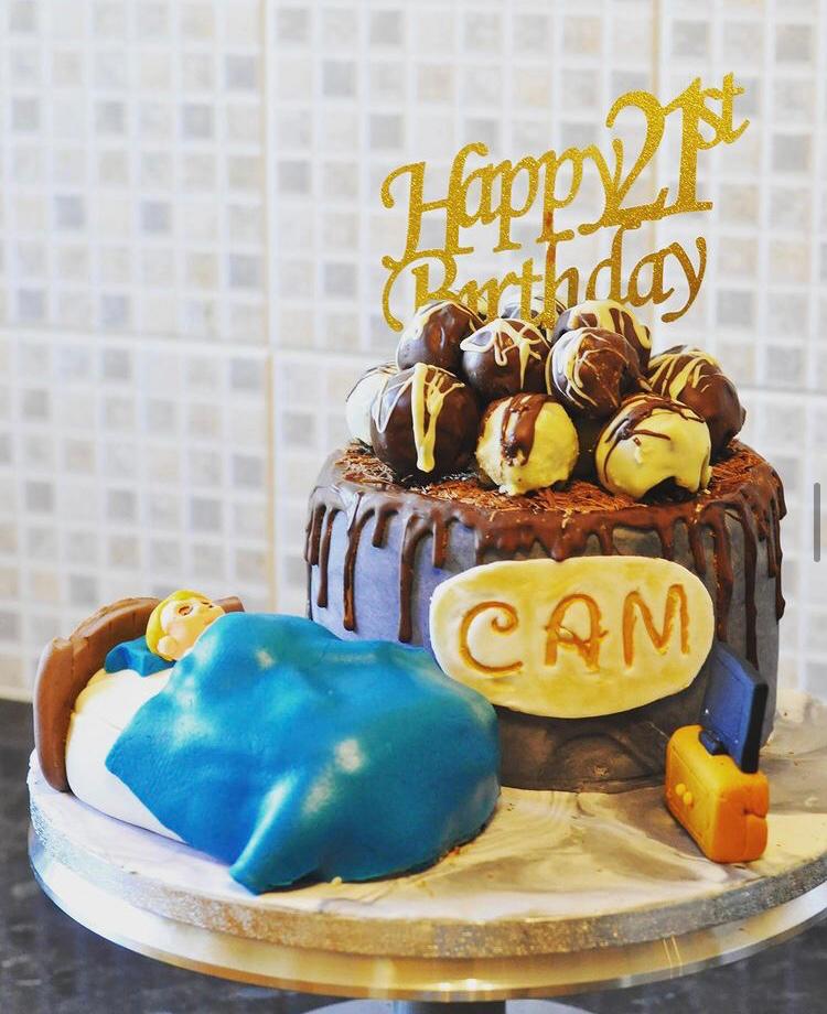 Multi-tiered chocolate birthday cake with a gold decoration reading 'Happy 21st Birthday Cam' 