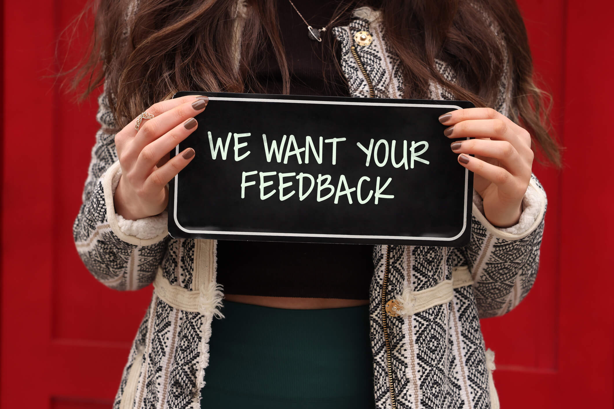 Female holding a sign saying 'we want your feedback'