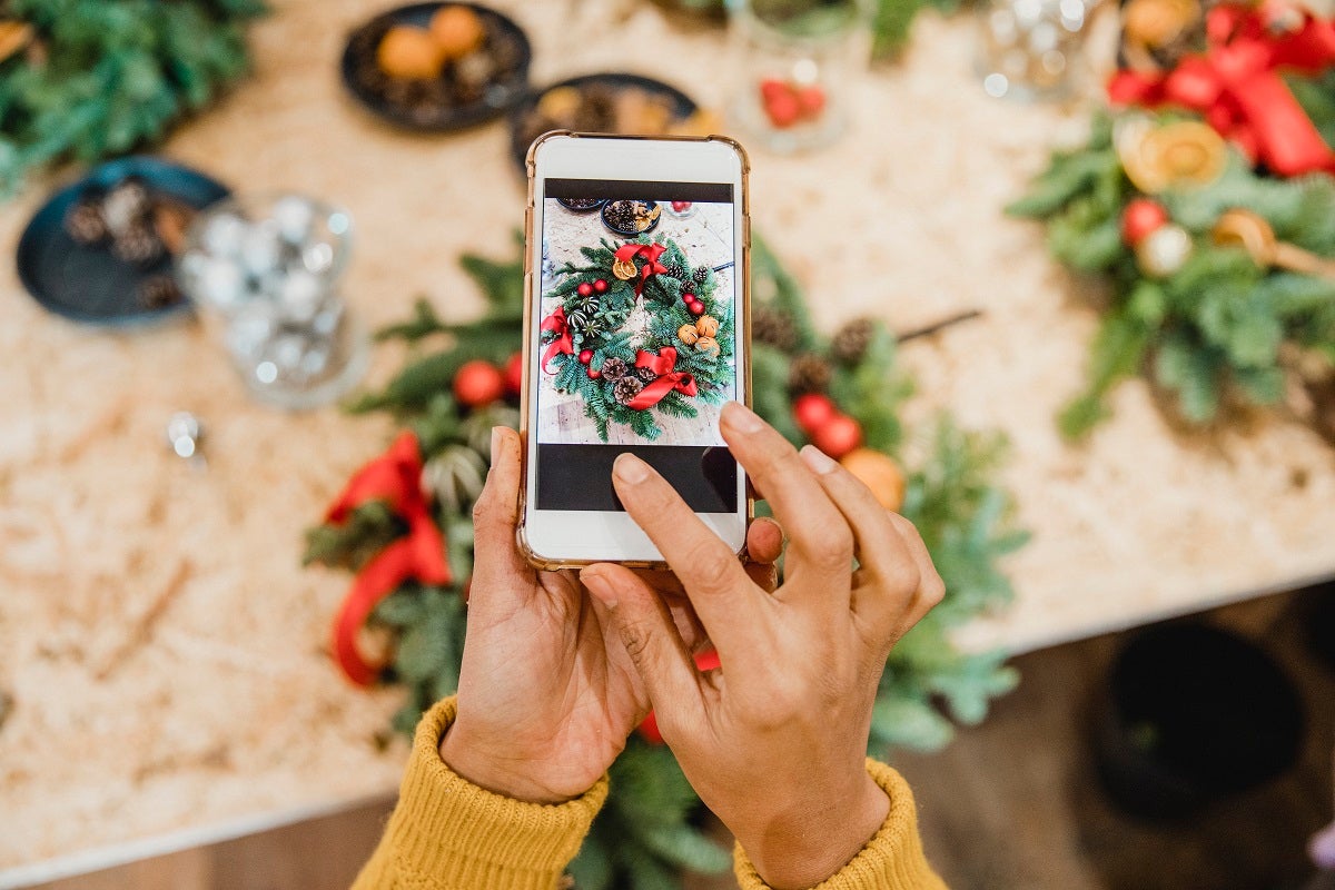 A closeup of someone taking a picture of a Christmas wreath with their phone