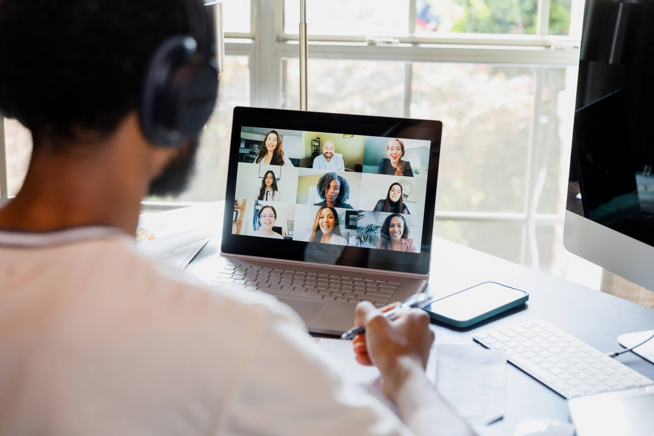 An over-the-shoulder view of a remote worker meeting online with colleagues