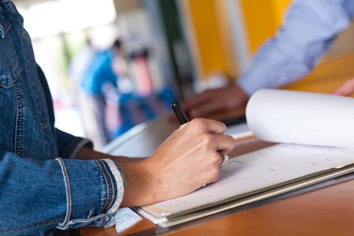 Woman in denim jacket fills out a registration form to register her business