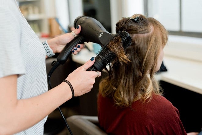 A hairdresser in Nottingham blow dries the hair of a client