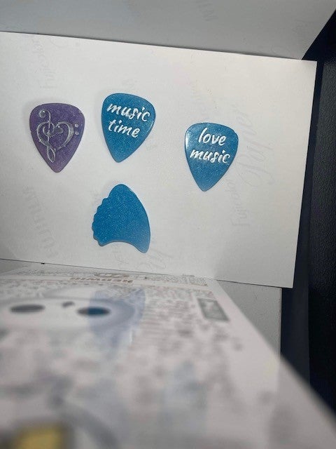 Some of Debbie's creations; an assortment of resin guitar picks in blue and purple with silver designs