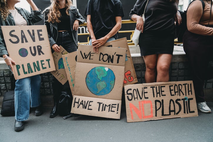 A group of people hold 'save the environment' signs up