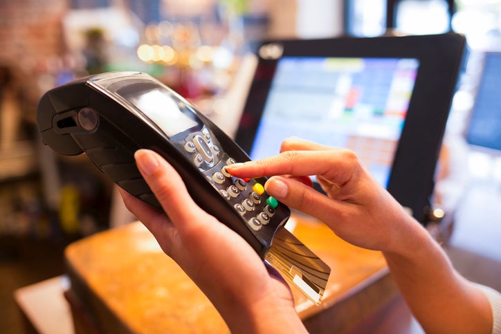 Hands holding a credit card reading machine in a shop. Is it a genuine customer or an example of card fraud?